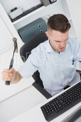 Frustrated man hitting computer monitor / keyboard with hammer