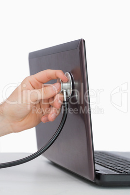 Hand examining laptop with stethoscope