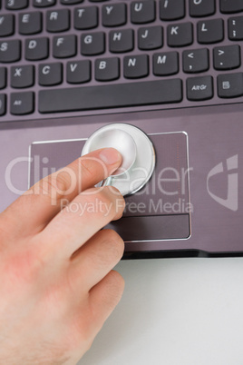 Hand examining touch pad of a laptop with stethoscope