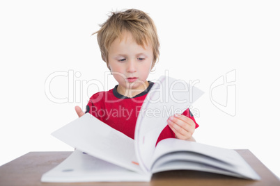 Little boy sitting at desk and reading book