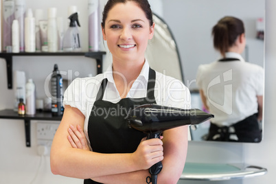 Confident female hairdresser holding hair dryer