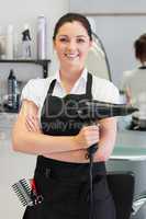 Confident female hairdresser holding hair dryer