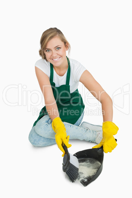 Portrait of smiling maid using brush and dust pan