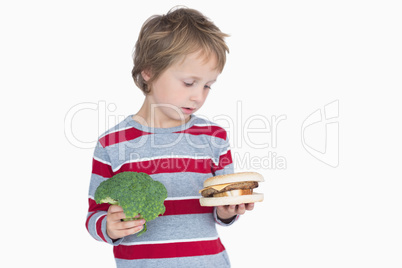 Young boy holding broccoli and burger