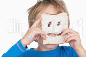 Young boy looking through holes in bread slice