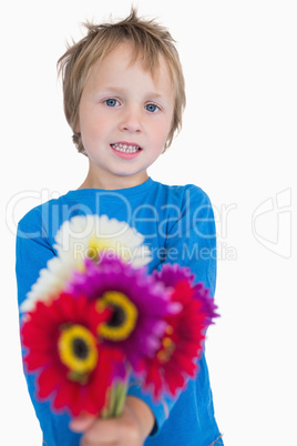 Portrait of cute young boy holding out flowers