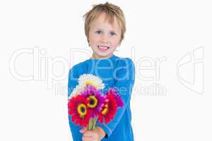 Portrait of cute young boy holding out flowers