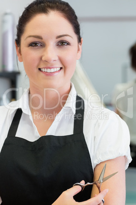 Happy female hairdresser with hair scissors