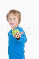 Portrait of young boy holding out a green apple