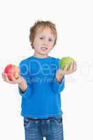 Portrait of young boy holding out green and red apples