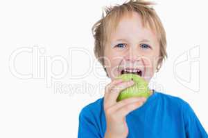 Portrait of young boy eating green apple