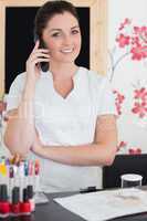 Woman answering phone at reception of nail salon