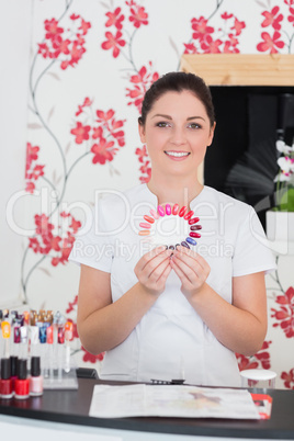 Smiling woman holding nail shades at salon