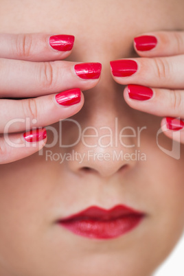Macro shot of young woman covering eyes with red painted finger