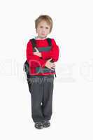 Young boy with schoolbag and book standing