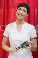 Young woman with hairbrush over red backdrop