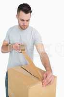 Man sealing cardboard box with packing tape