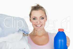 Smiling woman with clothes and washing powder bottle