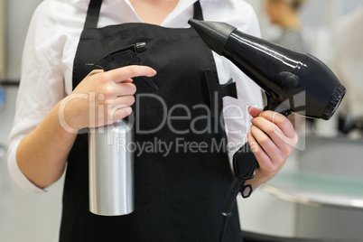 Hairdresser with hair dryer and spray
