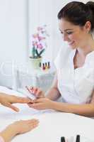Manicurist using nail brush on woman's nails