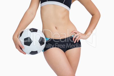 Midsection of fit woman in sportswear with football