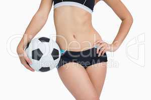 Midsection of fit woman in sportswear with football