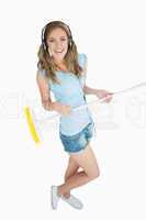 Young woman with broom enjoying music over headphones