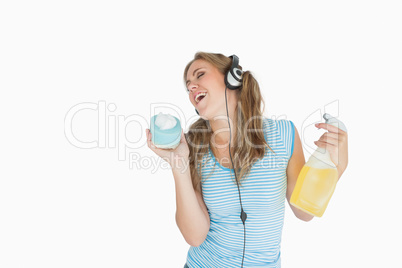 Woman with sponge and spray bottle enjoying music over headphone