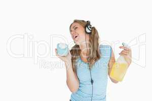 Woman with sponge and spray bottle enjoying music over headphone