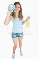 Woman with sponge and spray bottle listening music over headphon