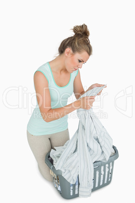 Woman looking at shirt collar with laundry basket