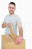 Portrait of man sealing cardboard box with packing tape
