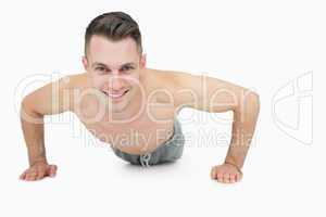 Portrait of happy shirtless man doing push ups