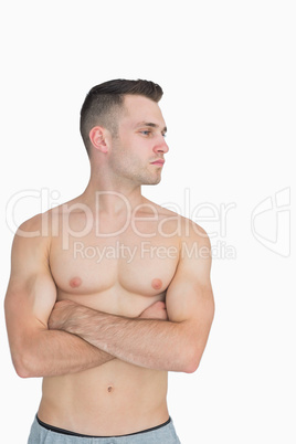 Bare chested man with arms crossed looking to his side