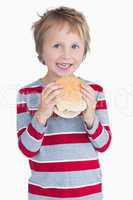 Cute happy young boy holding burger