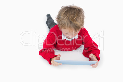 Little boy lying on floor and using digital tablet