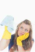 Bored young maid in yellow gloves using duster