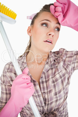 Tired young woman holding broom