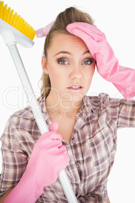 Portrait of tired young woman holding broom