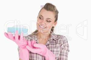Smiling young woman holding soap suds over sponge