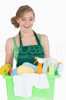 Happy young maid carrying cleaning supplies
