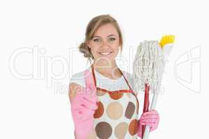 Portrait of maid with cleaning supplies gesturing thumbs up sign