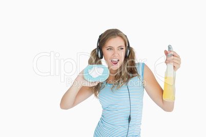 Young woman with sponge and spray bottle enjoying music over hea