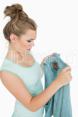 Displeased young woman looking at stained shirt