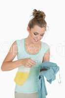 Young woman with spray bottle and stained shirt