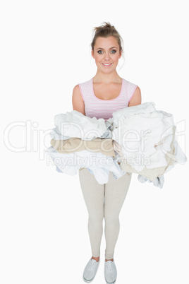 Portrait of smiling woman carrying stack of clothes