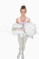 Portrait of young woman carrying stack of clothes