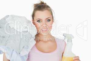 Smiling young woman with clothes and spray bottle