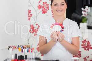 Smiling woman holding nail shades at salon