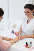 Manicurist filing woman's nails